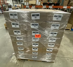 Shrink-wrapped pallet of Aqua Emergency canned water cases in a warehouse