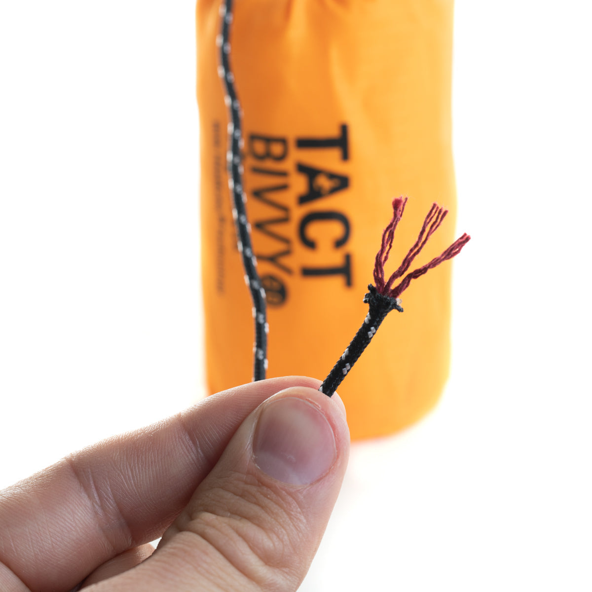 orange bivy in background with para tinder para cord cut open