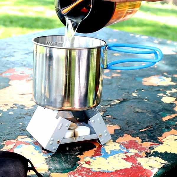 Pocket Stove being used outside with water pouring out into camp cup