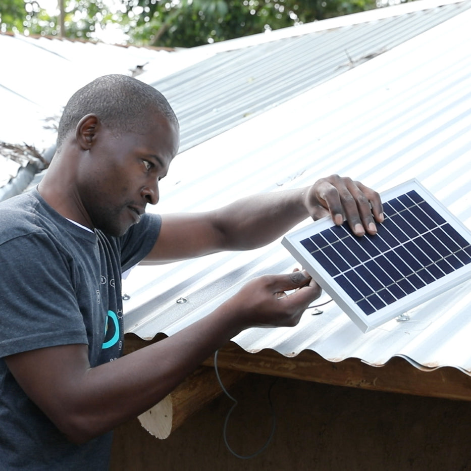 Man installing solar panel outside on roof BioLite Solar Home 620 Kit