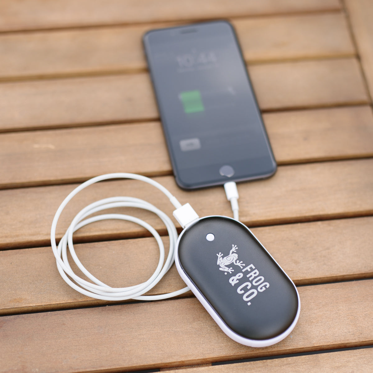 Electric Hand Warmer charging cell phone on table