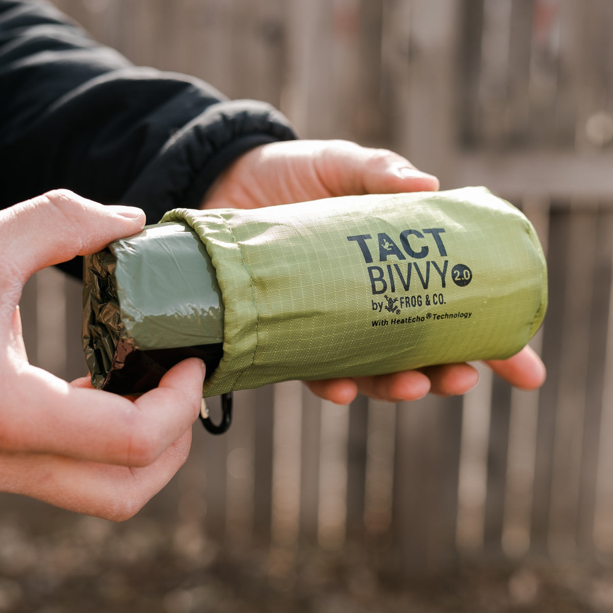 outdoor green bivy in hand taking out of bag