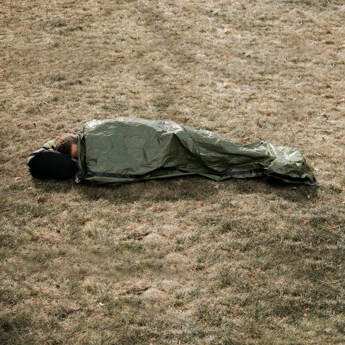 outdoor man in green bivy on ground