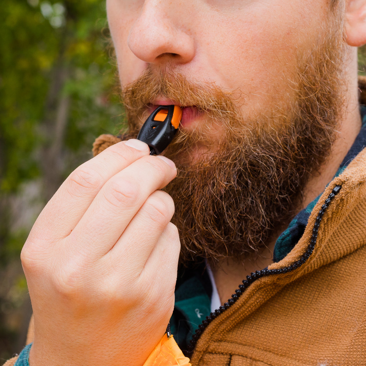 Man using scream whistle that is attached to lighter lanyard